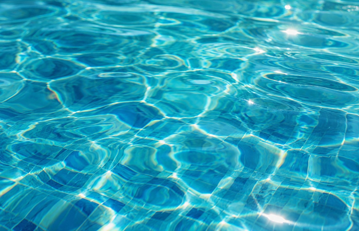 Close-up of crystal-clear turquoise pool water with sunlight caustics